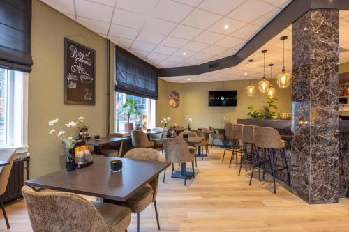 a restaurant with tables and chairs and a bar at Fletcher Hotel Apeldoorn in Apeldoorn