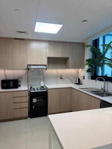 a kitchen with wooden cabinets and a black stove top oven at Luxury Beachfront Apartments by VB Homes in Ras al Khaimah