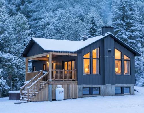 a house with a large deck in the snow at Spa & River - Le Zenith in Saint Come