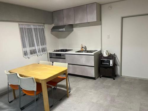 eine Küche mit einem Tisch, einem Herd und einer Spüle in der Unterkunft Miya's Home 102-名駅まるまる貸切メゾン in Nagoya