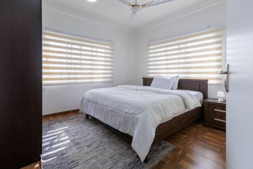 a bedroom with a large bed and two windows at Maseru Apartments in Bawaleshi
