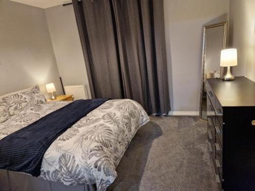 a bedroom with a bed and a dresser and a window at Morden 2 Bed Apartment, with parking near city centre in Coventry