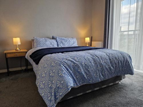 a bedroom with a bed with a blue comforter and a window at Morden 2 Bed Apartment, with parking near city centre in Coventry