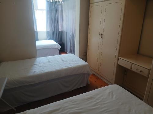 a small bedroom with two beds and a cabinet at 16 Laburnum lodge in Durban