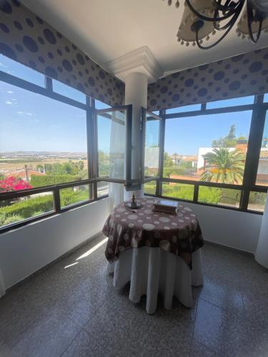 a dining room with a table and large windows at Villa Familia in Écija