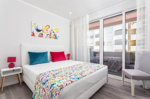 ein weißes Schlafzimmer mit einem Bett und einem Stuhl in der Unterkunft Luxury Beach Apartment at Armação de Pêra in Armação de Pêra