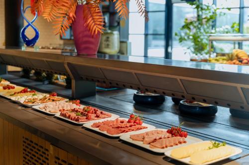 a buffet line with plates of meats and cheese at Corendon Amsterdam Schiphol Airport, a Tribute Portfolio Hotel in Badhoevedorp