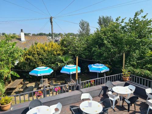 a patio with tables and chairs and umbrellas at The Thirsty Scholar in Penryn