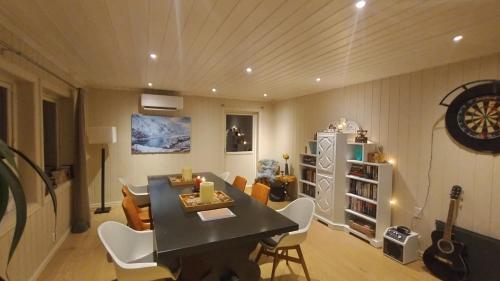 een eetkamer met een tafel en stoelen en een gitaar bij Skap Opplevelser! in Svingvoll