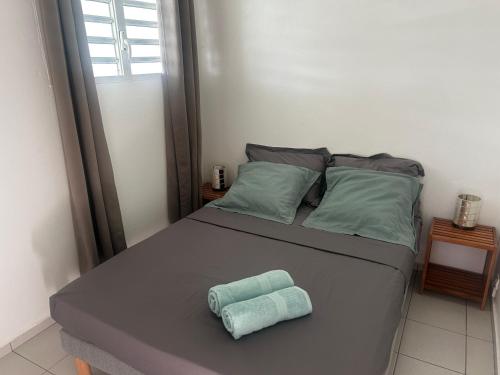 a bed with two folded towels on top of it at Les lodges couleur caraïbes in Saint-François