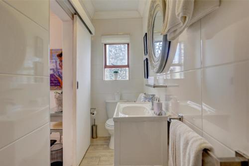 a white bathroom with a sink and a mirror at Stay Wilderness in Wilderness
