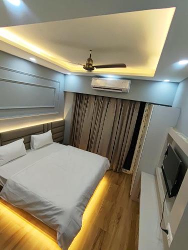 a bedroom with a white bed and a television at Anantya Inn in Greater Noida