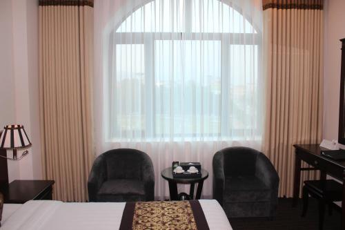 a hotel room with a bed and two chairs and a window at Hai Yen Luxury Hotel in Cẩm Phả
