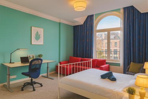 a bedroom with a bed and a desk and a bed and a chair at Flora's Palace - The Hague Scheveningen in The Hague