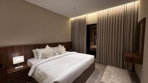Un dormitorio con una cama grande con sábanas y almohadas blancas. en JA Accom, en Al ‘Ayn