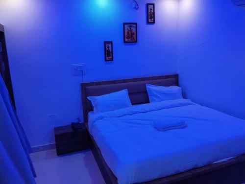 a blue bedroom with a large bed with white sheets and pillows at Hotel 7R RESIDENCY in Jhānsi