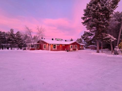 a red house with snow on the ground in front at Kaamasen Kievari in Kaamanen
