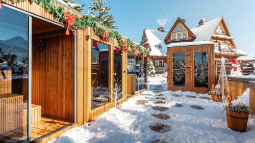een rij houten huizen in de sneeuw bij Villa Delta Boutique in Kościelisko