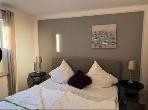 a bedroom with a bed with white sheets and pillows at Design Wohnung in Petersdorf auf Fehmarn