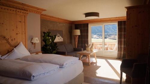 a bedroom with a bed and a couch and a window at Hotel Hohenfels in Tannheim