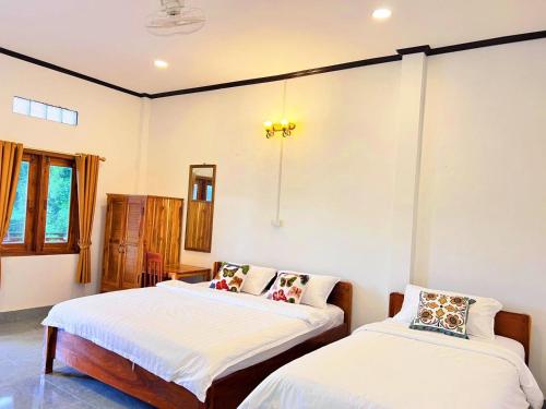 Dos camas en una habitación con paredes blancas. en phoulisack2 guesthouse, en Nongkhiaw