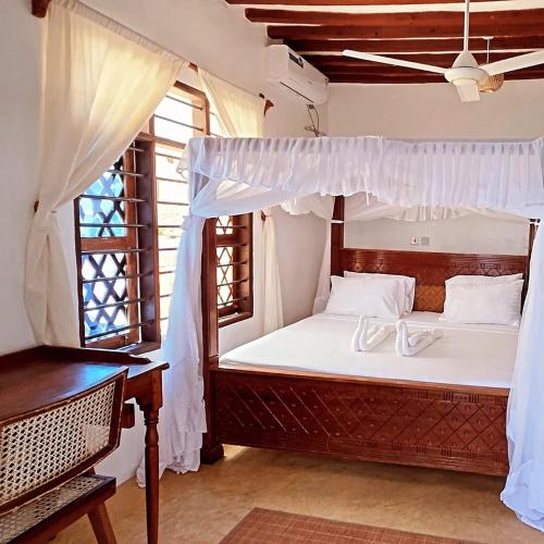 a bedroom with a bed with white sheets and a window at AMOODY MANZIl in Shela