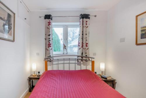 1 dormitorio con 1 cama con colcha rosa en 1 Bed in Hindhead oc-w34256, en Hindhead
