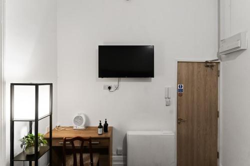 a room with a desk and a television on a wall at Cheerful Central Studio - 2 in Leicester