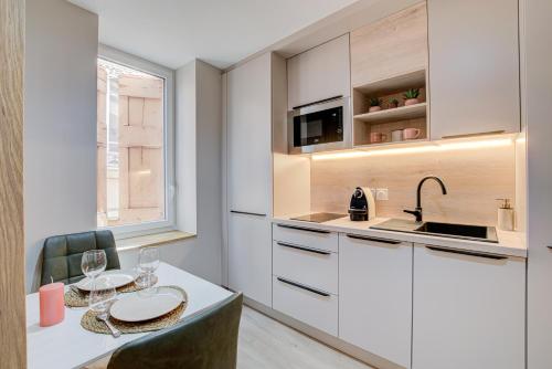 a kitchen with white cabinets and a table with wine glasses at Serenity Suite in Bourgoin