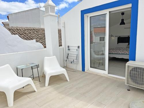 a patio with white chairs and a sliding glass door at Tiny Townhouse Tavira By Junto ao Mar in Tavira