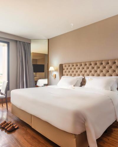 a large white bed in a hotel room at Ouro Minas Hotel Belo Horizonte, Dolce by Wyndham in Belo Horizonte