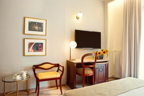 Una habitación de hotel con un escritorio con televisión y dos sillas. en Zeus Essence Bucharest Venezia, en Bucarest