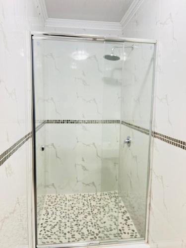a shower with a glass door in a bathroom at Nakawa Guest Lodge in Brakpan