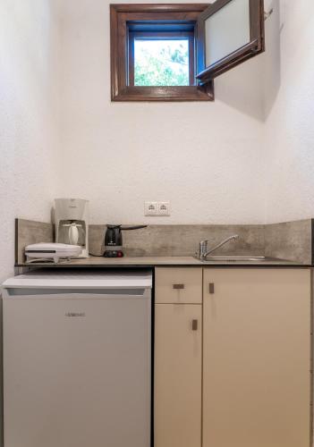 a kitchen with white cabinets and a sink and a window at Villa Spartias in Skiathos