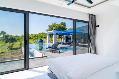 Peaceful 4Br Luxury Villa Elena Walk to Beach في Ban Hua Laem Ma So: غرفة نوم مع سرير وإطلالة على المسبح