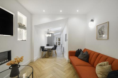 a living room with an orange couch and a table at Stylish Kentish Town HomePrivate Garden Jacuzzi in London
