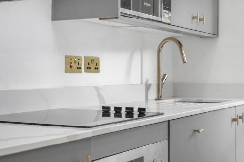 a white kitchen with a sink and a counter top at Stylish Kentish Town HomePrivate Garden Jacuzzi in London