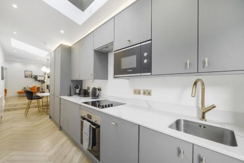 a kitchen with white cabinets and a sink at Stylish Kentish Town HomePrivate Garden Jacuzzi in London