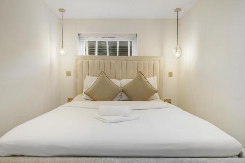 a bedroom with a large white bed with two lights at Stylish Kentish Town HomePrivate Garden Jacuzzi in London