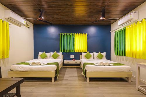 two beds in a room with yellow curtains at Kokanwadi Resort in Ratnagiri