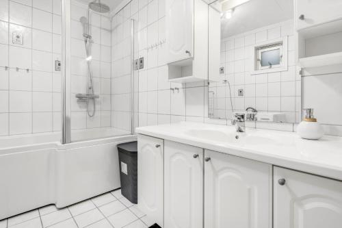 a white bathroom with a sink and a shower at Apartment with view of the city in Hjorten