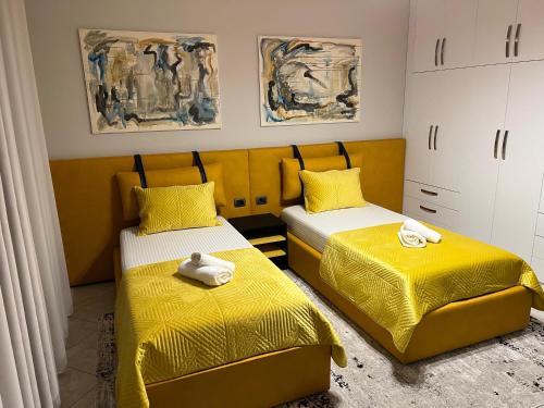 a bedroom with two beds with yellow sheets at Manga Luxury Apartments - 2 Bedrooms in Gjirokastër
