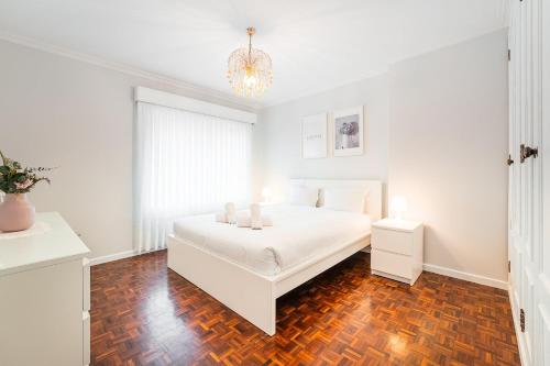 a white bedroom with a bed and a chandelier at GuestReady - Urban rustic in Esposende in Esposende