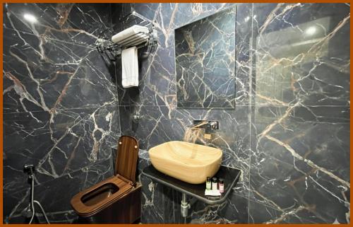 a bathroom with a wooden toilet and a marble wall at Hotel Shri RK Residency Near Kashi Vishwanath Temple - Fully Air Conditioning Rooms - Restaurant-Lift and Free Wifi Facilities- Top Rated Hotel In Varanasi in Kashi