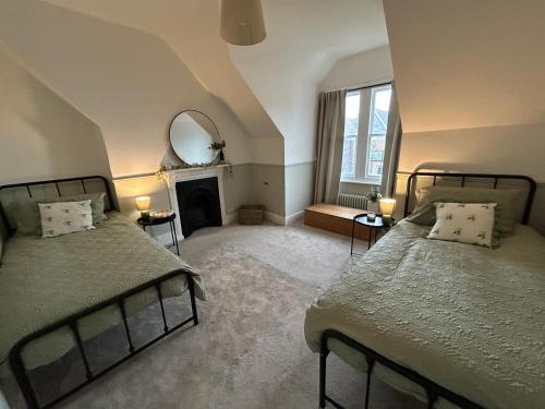 1 dormitorio con 2 camas, espejo y chimenea en Seaside apartment, en Bexhill-on-Sea