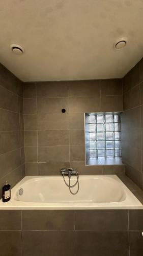 eine weiße Badewanne in einem Badezimmer mit Fenster in der Unterkunft Laventure in Aywaille