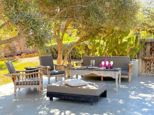 a patio with furniture and a table and a tree at Palais Tiyana in Al Ghar
