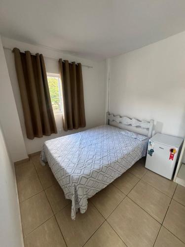 a bedroom with a bed and a small refrigerator at Família Ebeneze in Nova Friburgo