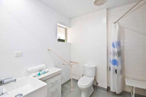 a white bathroom with a toilet and a sink at Bay View Ocean Views in Lorne