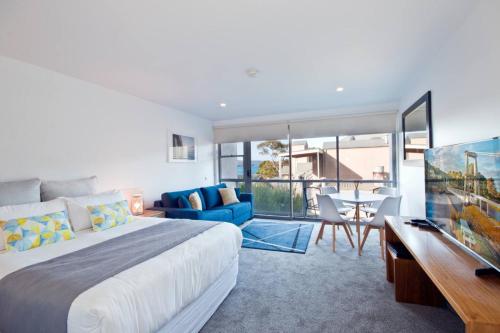 a bedroom with a large bed and a dining room at Bay View Ocean Views in Lorne